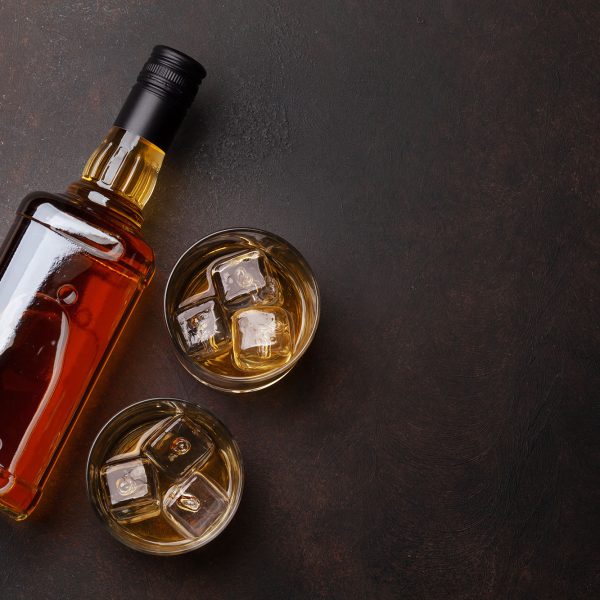 Scotch whiskey bottle and glasses on stone table. With copy space. Top view flat lay